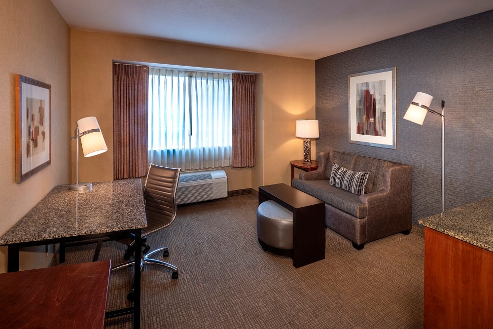 view of hotel room desk, couch and window