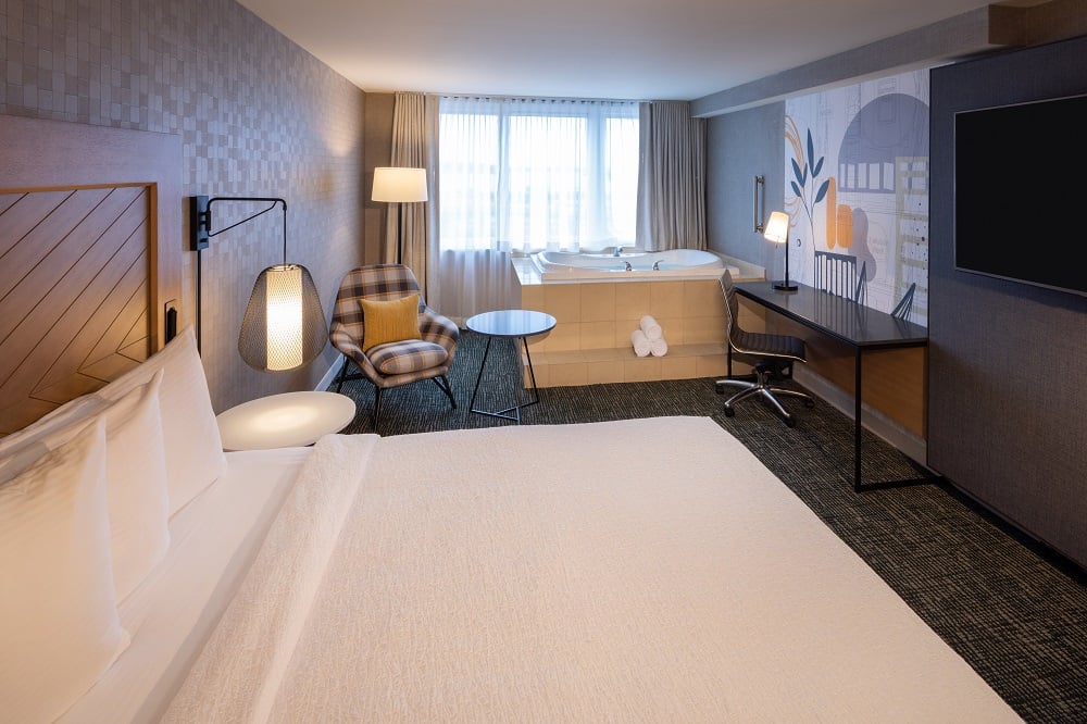 hotel room with king bed and jacuzzi tub in front of window