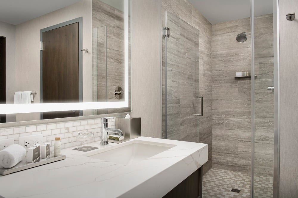 hotel bathroom with walk in shower and marble countertops