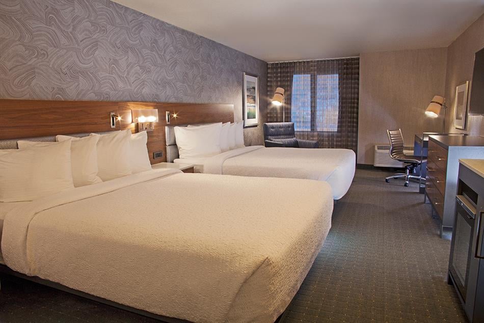 hotel room with two queen beds, desk and dresser