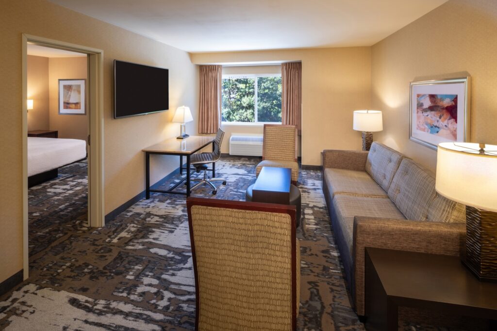 Hotel room living space with couch, chairs, desk and TV