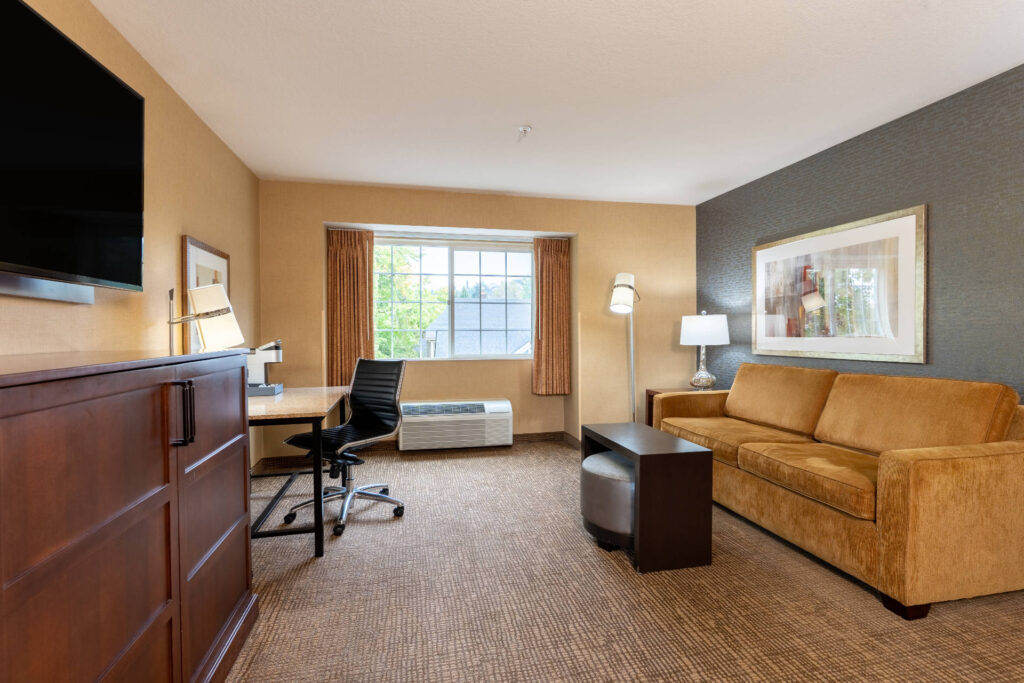 Deluxe King Room at Silver Cloud Hotel Portland with a comfortable seating area, work desk, flat-screen TV, and large window providing natural light.