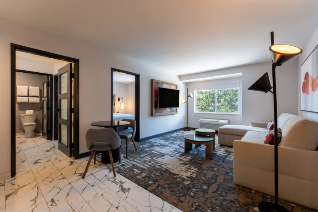 Modern guest room sitting area at Silver Cloud Hotel University District with sofa, desk, and large window.